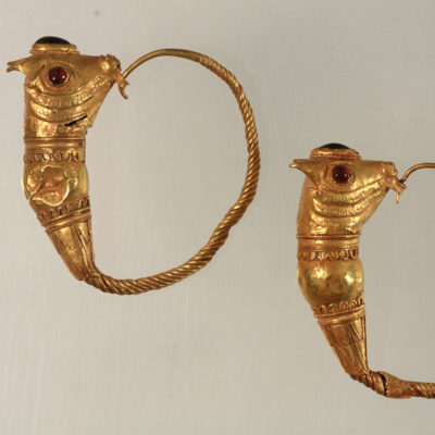 Gold earrings made of twisted wire ending in a bull’s head with inlaid garnets for the eyes (1147).