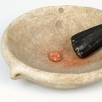 Marble bowl with a lump of red pigment and an obsidian pestle.
